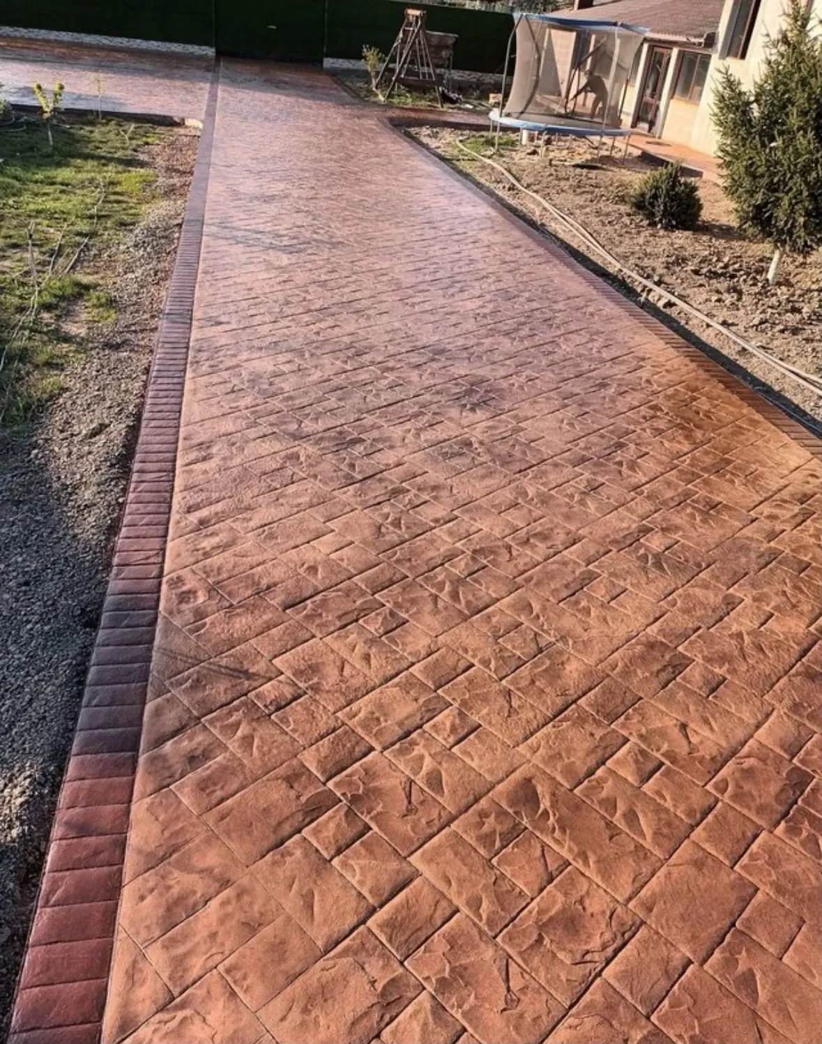 Camino de hormigón impreso con molde de sileria pequeña en terracota y cenefa oscura