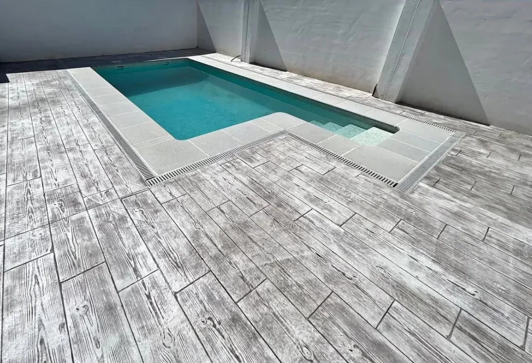 Piscina rodeada de hormigón impreso imitación madera en gris claro